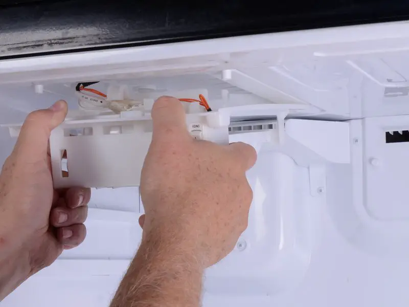 image of person hand holding ice maker for removing it.