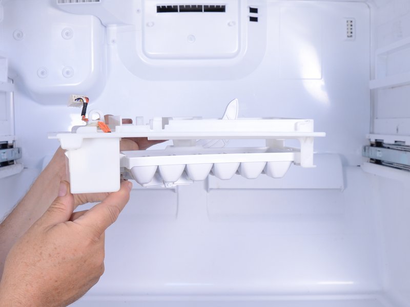 image of a person hand which hold the ice maker of a fridge after unplug.